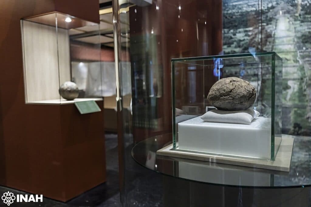 Pelota de hule de 3,600 años exhibida en vitrina en la exposición Hule ritual: pelotas milenarias en Teotihuacan.