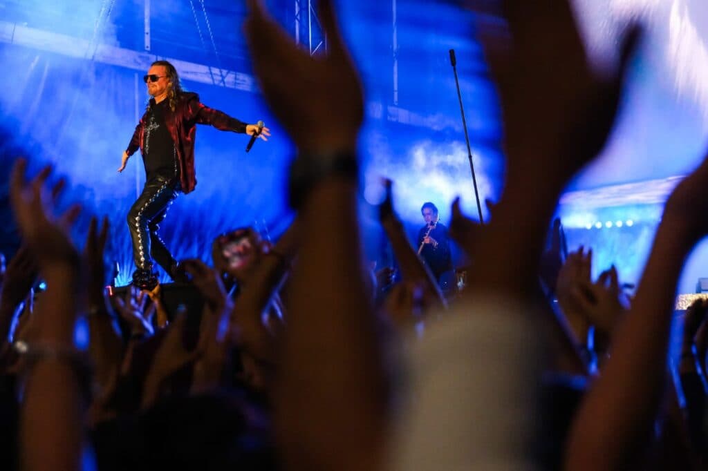 Vocalista de Maná en un concierto en La Minerva, con el público levantando las manos en un ambiente festivo y de celebración.