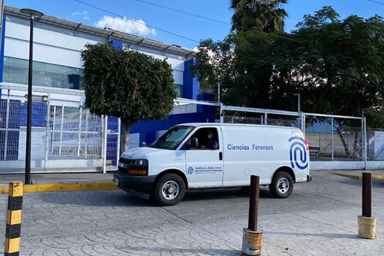 Furgón de Ciencias Forenses frente a un edificio en Jalisco, utilizado para la identificación de personas en inhumaciones clandestinas.