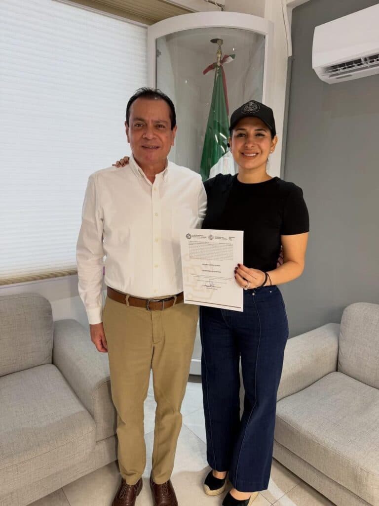 Estefanía Mercado y Arturo Castro posan sonrientes con el documento de designación en la nueva Secretaría de Gobierno en Playa del Carmen.