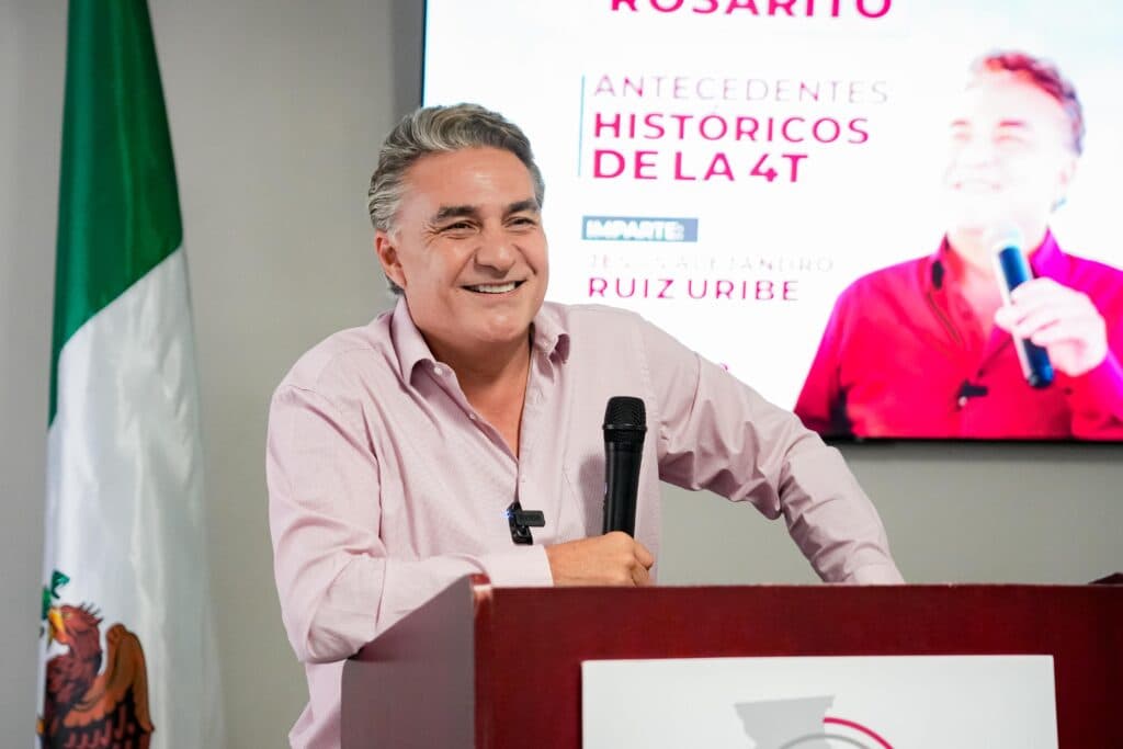Jesus Ruiz Uribe sonríe mientras habla en un evento de MORENA en Casa Morena, Rosarito, con una presentación sobre la Cuarta Transformación.