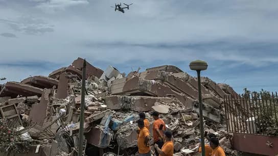Rescatistas trabajan entre escombros de un edificio colapsado tras los terremotos en Venezuela, mientras un dron sobrevuela la zona.