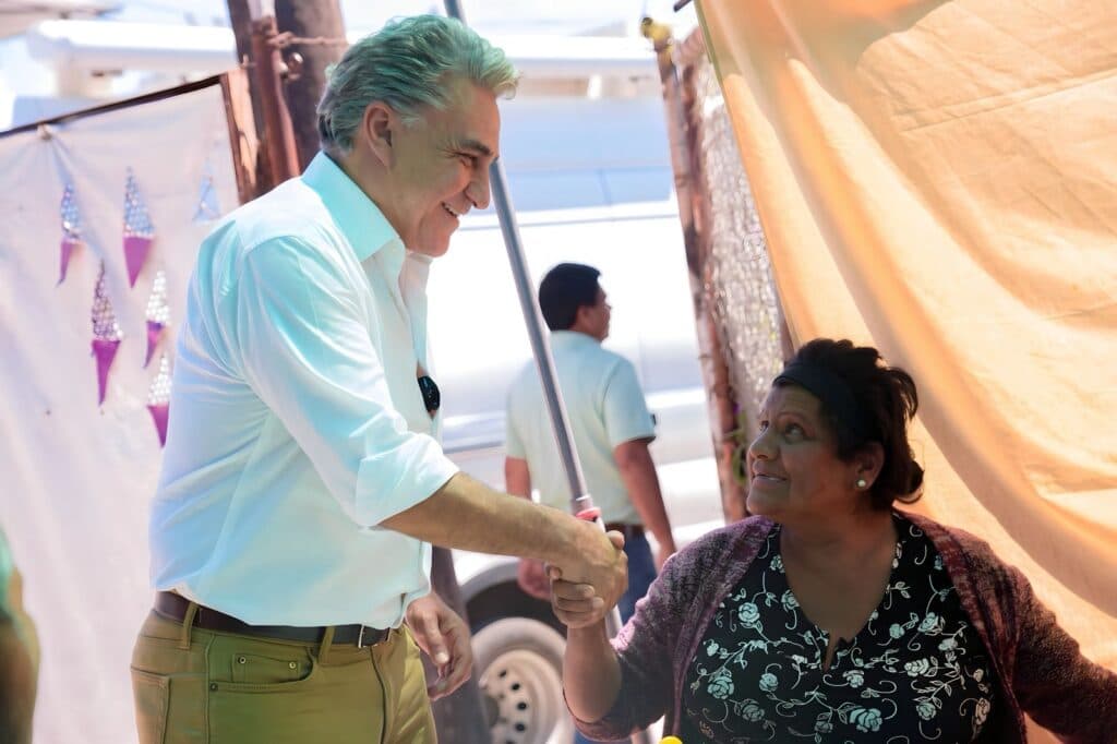 Jesús Ruiz Uribe estrecha la mano de una mujer en el Club de la Alegría, promoviendo la defensa de la soberanía nacional.