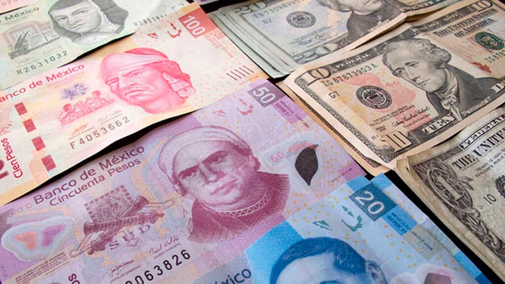 Billetes de pesos mexicanos y dólares estadounidenses sobre una superficie, ilustrando el tipo de cambio y la economía.