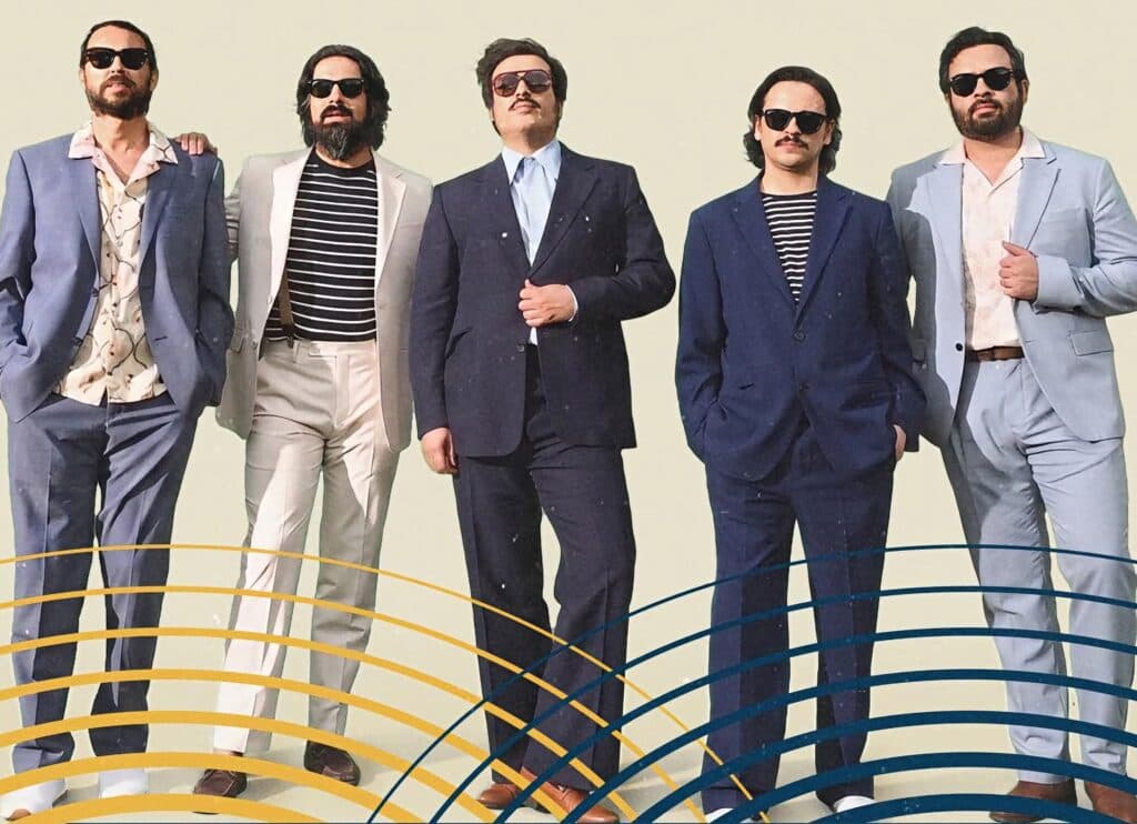La banda mexicana Enjambre posando en trajes elegantes, listos para su concierto gratuito en el Zócalo de la CDMX.