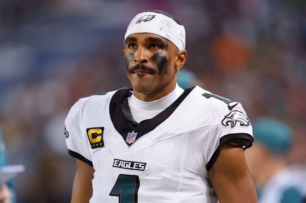 Jalen Hurts, quarterback de los Philadelphia Eagles, con expresión seria durante un partido de la NFL, luciendo uniforme y cinta en la cabeza.