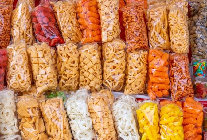 Variedad de alimentos envasados, incluyendo botanas y dulces, que podrían verse afectados por la prohibición de comida chatarra en escuelas.