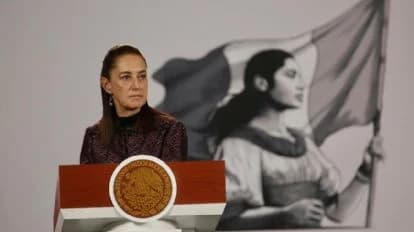 Claudia Sheinbaum durante su conferencia matutina, con un fondo que muestra a una mujer sosteniendo una bandera mexicana.